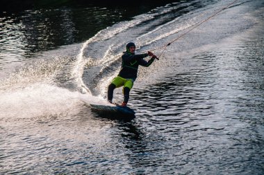 Gün batımında Tibet öküzü kostümü giymiş bir adam Kiev 'deki aşırı parktaki bir wakeboard üzerinde sıçrama tahtasından atlıyor. Ukrayna. Yüksek kalite fotoğraf