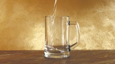 Saf su büyük şeffaf cam bardağa dökülür, ağır çekimde.