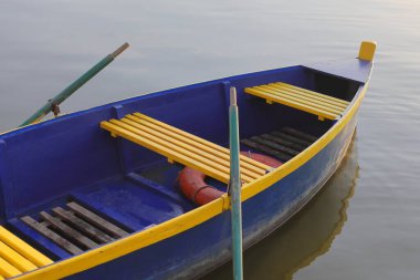 Günbatımında göl kenarındaki rıhtımda kürekleri olan bir tekne.