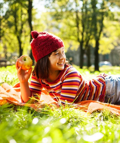 Carino ragazza felice su erba verde con mela — Foto Stock