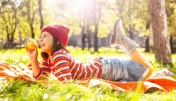 Ładny dziewczyna szczęśliwy na zielonej trawie z jabłkiem — Zdjęcie stockowe