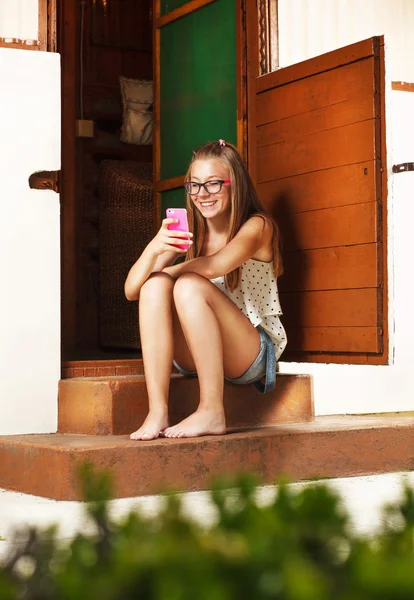 Adolescente sentada na frente da casa rural — Fotografia de Stock