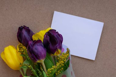 Doğum günü partisi için kartlar, anneler günü için davetiyeler, narin leylak rengi ve sarı lale çiçekli sevgililer günü kartları ve yanında beyaz boş bir zarf..