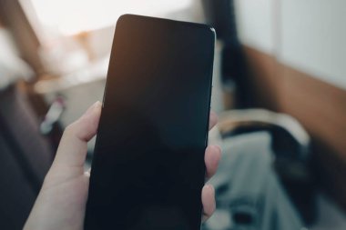 Elinde akıllı telefonları tutan bir kadın. Evinde boş siyah bir ekran.. 