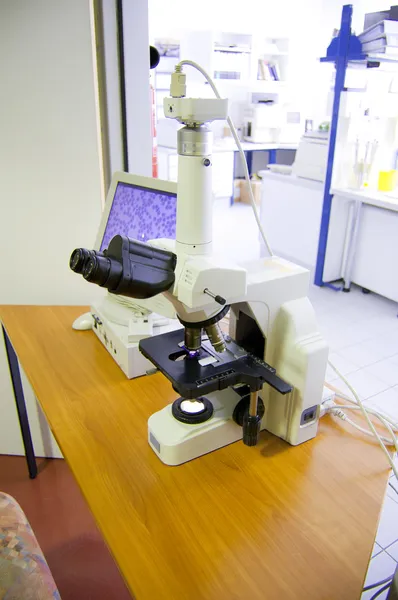 Microscopio analizando células en una muestra de sangre que se muestra en una pantalla del monitor — Foto de Stock