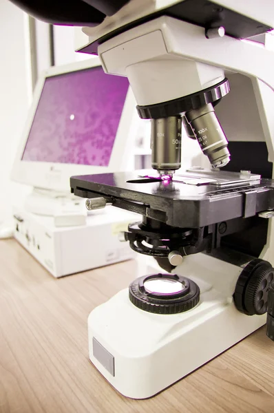 Microscopio analizando células en una muestra de sangre que se muestra en una pantalla del monitor — Foto de Stock