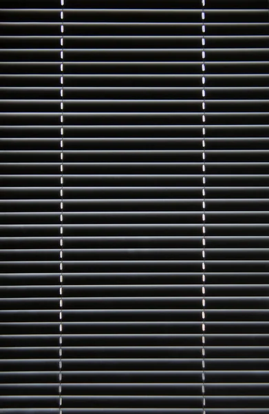 Window blinds hanging on the window in the closed position — Stock Photo, Image