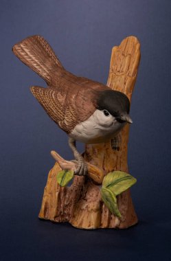 Bir dala oturmuş seramik bir serçe figürü.