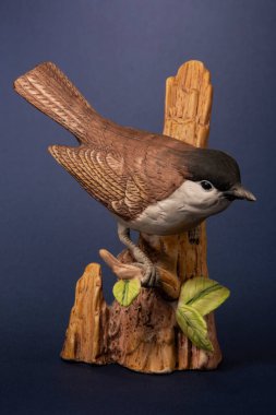 Bir dala oturmuş seramik bir serçe figürü.