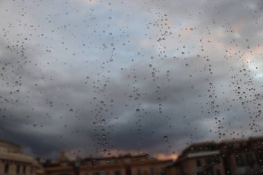 Cenova, İtalya - 28 Kasım 2021: Sonbaharda pencerenin üzerindeki su damlasına kadar güzel makro fotoğrafçılık. Pencereye yansıyan yağmur. Arka planda gri gökyüzü.