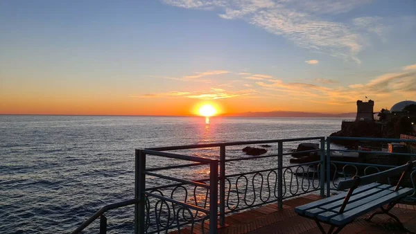 ジェノヴァ イタリア 2022年1月28日 冬の海の上に美しい夕日 赤い色の雲が水面に反射した 岩の近くの小さな波 — ストック写真