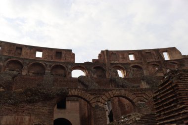ROME, ITALY - 05 Şubat 2022: Roma, İtalya 'da Colosseum' un iç kısmının panoramik görüntüsü. Arka planda soğuk ve gri gökyüzü. Kemerlerin makro fotoğrafları.