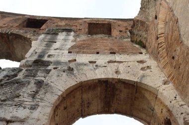 ROME, ITALY - 05 Şubat 2022: Roma, İtalya 'da Colosseum' un iç kısmının panoramik görüntüsü. Arka planda soğuk ve gri gökyüzü. Kemerlerin makro fotoğrafları.
