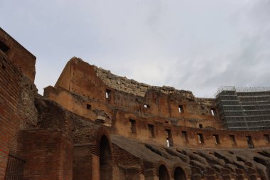 ROME, ITALY - 05 Şubat 2022: Roma, İtalya 'da Colosseum' un iç kısmının panoramik görüntüsü. Arka planda soğuk ve gri gökyüzü. Kemerlerin makro fotoğrafları.