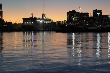 Cenova, İtalya - 22 Şubat 2022: Cenova (Cenova) limanının iskele vinçleri ve sanayi bölgesi ile akşam manzarası. Ceneviz, İtalya. Geceleri fener ışıkları. Şehir denizin arkasında aydınlandı..