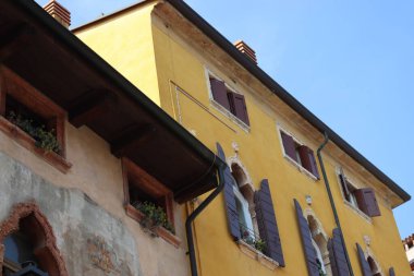 Verona, İtalya-19 Mart 2022: Verona 'nın güzel eski binaları. Ortaçağ 'ın tipik mimarisi. Arka planda mavi gökyüzü olan şehre hava görüntüsü.