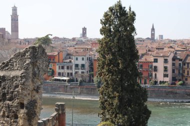 Verona, İtalya-19 Mart 2022: Verona 'nın güzel eski binaları. Ortaçağ 'ın tipik mimarisi. Arka planda mavi gökyüzü olan şehre doğru hava manzarası, nehre ulaşmak için güzel bir manzara..