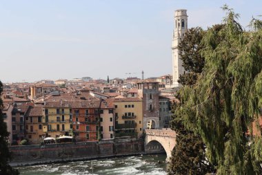 Verona, İtalya-19 Mart 2022: Verona 'nın güzel eski binaları. Ortaçağ 'ın tipik mimarisi. Arka planda mavi gökyüzü olan şehre doğru hava manzarası, nehre ulaşmak için güzel bir manzara..