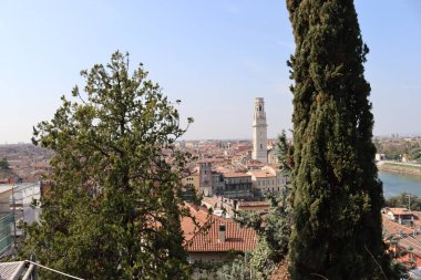 Verona, İtalya-19 Mart 2022: Verona 'nın güzel eski binaları. Ortaçağ 'ın tipik mimarisi. Arka planda mavi gökyüzü olan şehre doğru hava manzarası, nehre ulaşmak için güzel bir manzara..