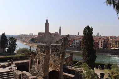 Verona, İtalya-19 Mart 2022: Verona 'nın güzel eski binaları. Ortaçağ 'ın tipik mimarisi. Arka planda mavi gökyüzü olan şehre doğru hava manzarası, nehre ulaşmak için güzel bir manzara..