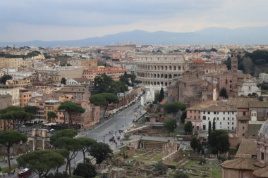 ROME, ITALY - 05 Şubat 2022: Roma, İtalya 'daki Colosseum çevresindeki panoramik manzara. Arka planda soğuk ve gri gökyüzü. Eski binalarla yeşil parkların makro fotoğrafları..