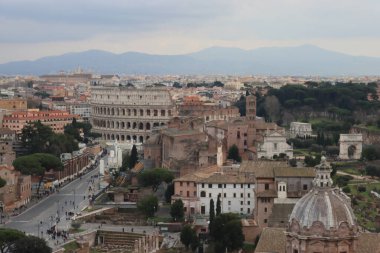 ROME, ITALY - 05 Şubat 2022: Roma, İtalya 'daki Colosseum çevresindeki panoramik manzara. Arka planda soğuk ve gri gökyüzü. Eski binalarla yeşil parkların makro fotoğrafları..