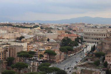 ROME, ITALY - 05 Şubat 2022: Roma, İtalya 'daki Colosseum çevresindeki panoramik manzara. Arka planda soğuk ve gri gökyüzü. Eski binalarla yeşil parkların makro fotoğrafları..