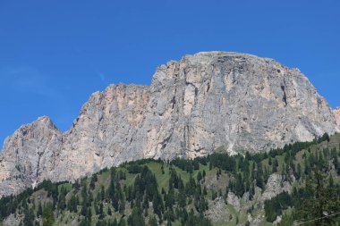 Coravara, Italy-July 16, 2022: The italian Dolomites behind the small village of Corvara in summer days with beaitiful blue sky in the background. Green nature in the middle of the rocks. 