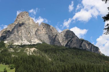 Coravara, Italy-July 16, 2022: The italian Dolomites behind the small village of Corvara in summer days with beaitiful blue sky in the background. Green nature in the middle of the rocks. 