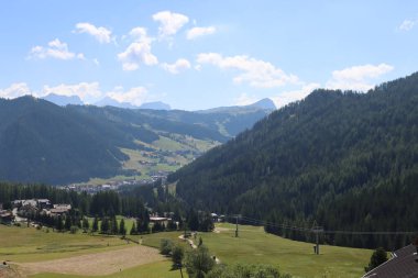 Coravara, Italy-July 16, 2022: The italian Dolomites behind the small village of Corvara in summer days with beaitiful blue sky in the background. Green nature in the middle of the rocks. 