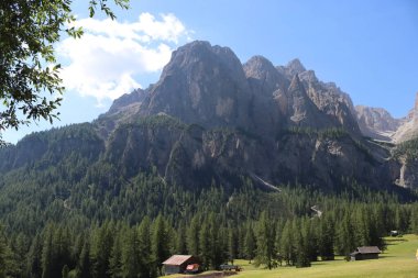 Coravara, Italy-July 16, 2022: The italian Dolomites behind the small village of Corvara in summer days with beaitiful blue sky in the background. Green nature in the middle of the rocks. 