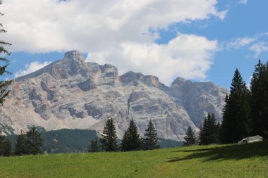 Coravara, Italy-July 16, 2022: The italian Dolomites behind the small village of Corvara in summer days with beaitiful blue sky in the background. Green nature in the middle of the rocks. 