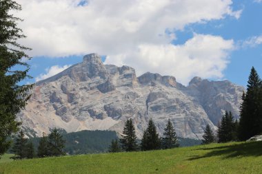 Coravara, Italy-July 16, 2022: The italian Dolomites behind the small village of Corvara in summer days with beaitiful blue sky in the background. Green nature in the middle of the rocks. 