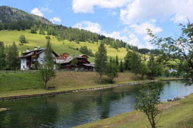 Coravara, Italy-July 16, 2022: The italian Dolomites behind the small village of Corvara in summer days with beaitiful blue sky in the background. Green nature in the middle of the rocks. 