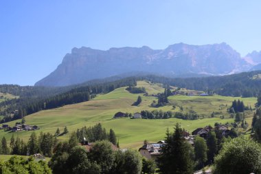 Val Badia, Italy-July 17, 2022: The italian Dolomites behind the small village of Corvara in summer days with beaitiful blue sky in the background. Green nature in the middle of the rocks.