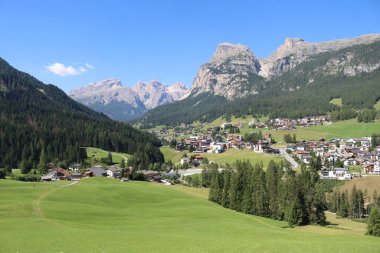 Val Badia, Italy-July 17, 2022: The italian Dolomites behind the small village of Corvara in summer days with beaitiful blue sky in the background. Green nature in the middle of the rocks.