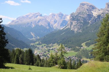 Val Badia, Italy-July 17, 2022: The italian Dolomites behind the small village of Corvara in summer days with beaitiful blue sky in the background. Green nature in the middle of the rocks.