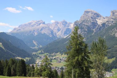Val Badia, Italy-July 17, 2022: The italian Dolomites behind the small village of Corvara in summer days with beaitiful blue sky in the background. Green nature in the middle of the rocks.