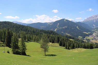 Val Badia, Italy-July 17, 2022: The italian Dolomites behind the small village of Corvara in summer days with beaitiful blue sky in the background. Green nature in the middle of the rocks.