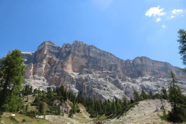 Val Badia, Italy-July 17, 2022: The italian Dolomites behind the small village of Corvara in summer days with beaitiful blue sky in the background. Green nature in the middle of the rocks.