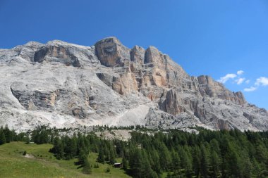 Val Badia, Italy-July 17, 2022: The italian Dolomites behind the small village of Corvara in summer days with beaitiful blue sky in the background. Green nature in the middle of the rocks.
