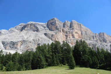 Val Badia, Italy-July 17, 2022: The italian Dolomites behind the small village of Corvara in summer days with beaitiful blue sky in the background. Green nature in the middle of the rocks.