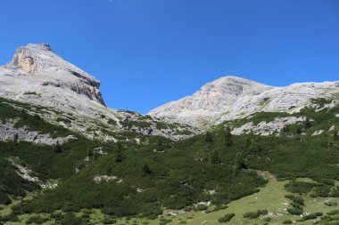 Val Badia, Italy-July 18, 2022: The italian Dolomites behind the small village of Corvara in summer days with beaitiful blue sky in the background. Green nature in the middle of the rocks.