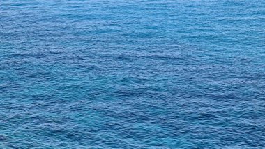 Cenova, Italy- 27 Temmuz 2022: mavi denizin panoraması, suyun üzerindeki ışık, okyanus gündoğumu. Kış günlerinde küçük dalgalar. Temiz gökyüzü suya yansıyor.