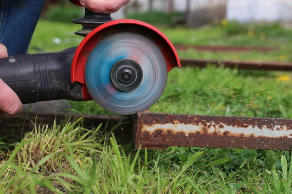 Bir işçi öğütücüyle metal keser. Uçan kıvılcımlar öğütüyor.