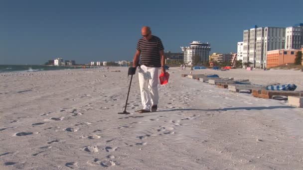 Senior férfi sétál a St. Pete beach egy fém detektor — Stock videók