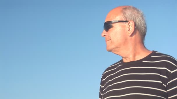 Senior man kijkt over de Oceaan. reflectie in zonnebril — Stockvideo