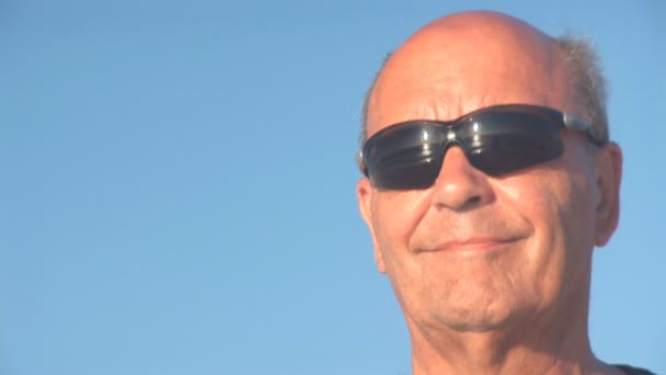 Senior man kijkt over de Oceaan. reflectie in zonnebril — Stockvideo