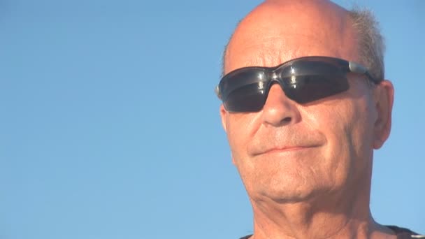 Starší muž vypadá přes oceán. odraz v sluneční brýle — Stock video