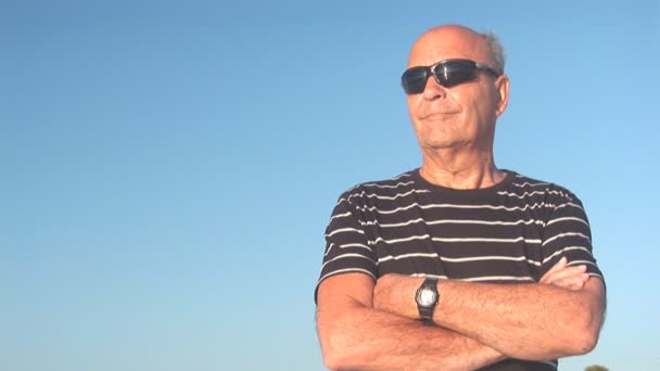 Senior man looks across the ocean. Reflection in sunglasses — Stock Video